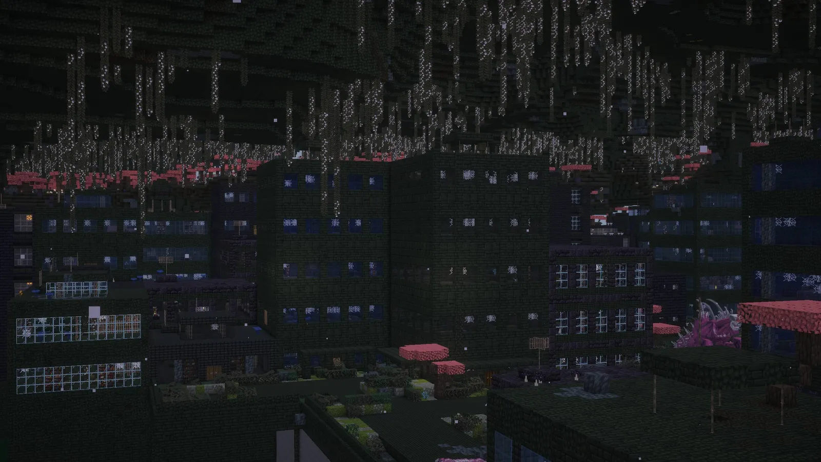 A ruined city at night, dark towers hung with vines over a lit street.